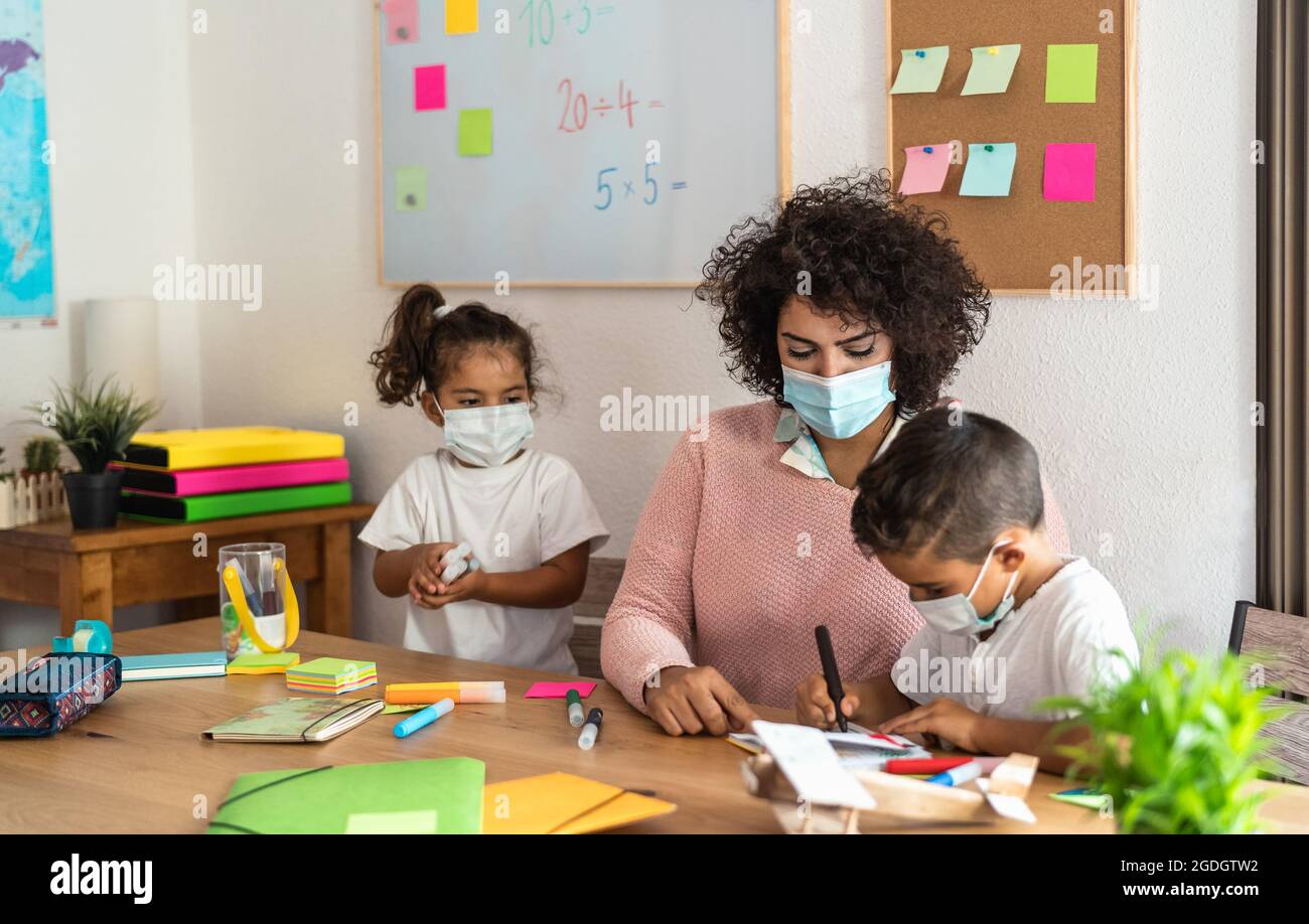 Lehrerin mit Kindern, die im Vorschulunterricht zeichnen, während sie Gesichtsschutzmaske während einer Corona-Virus-Pandemie tragen Stockfoto