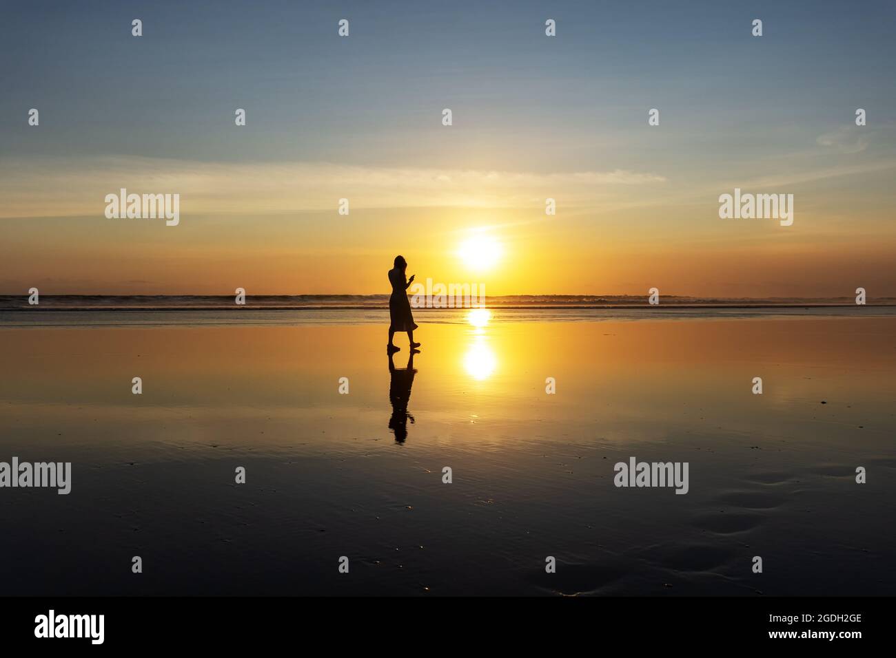 Kuta, Indonesien - 14. September 2018: Silhouette einer Frau, die am Seminyak-Strand auf Bali spazieren und den Sonnenuntergang genießen kann. Es ist eine der Touristenattraktionen in Stockfoto