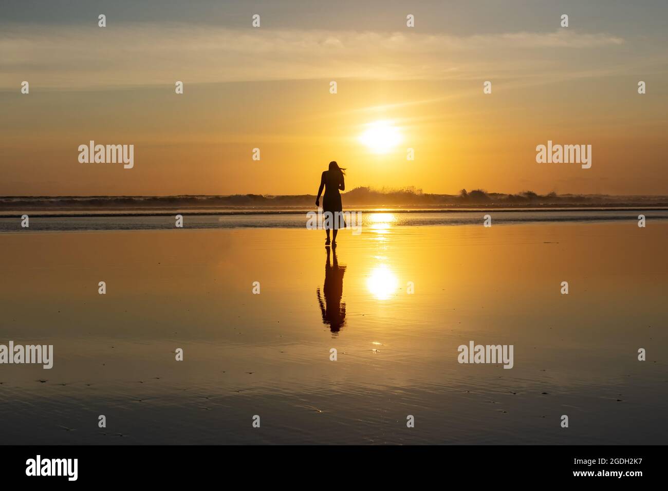 Kuta, Indonesien - 14. September 2018: Silhouette einer Frau, die am Seminyak-Strand auf Bali spazieren und den Sonnenuntergang genießen kann. Es ist eine der Touristenattraktionen in Stockfoto