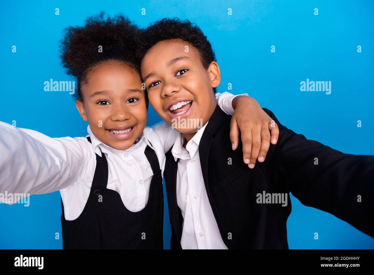 Foto von kleinen kleinen afro amerikanische Kinder machen Selfie tragen einheitliche Lächeln Umarmung isoliert auf blauem Hintergrund Stockfoto