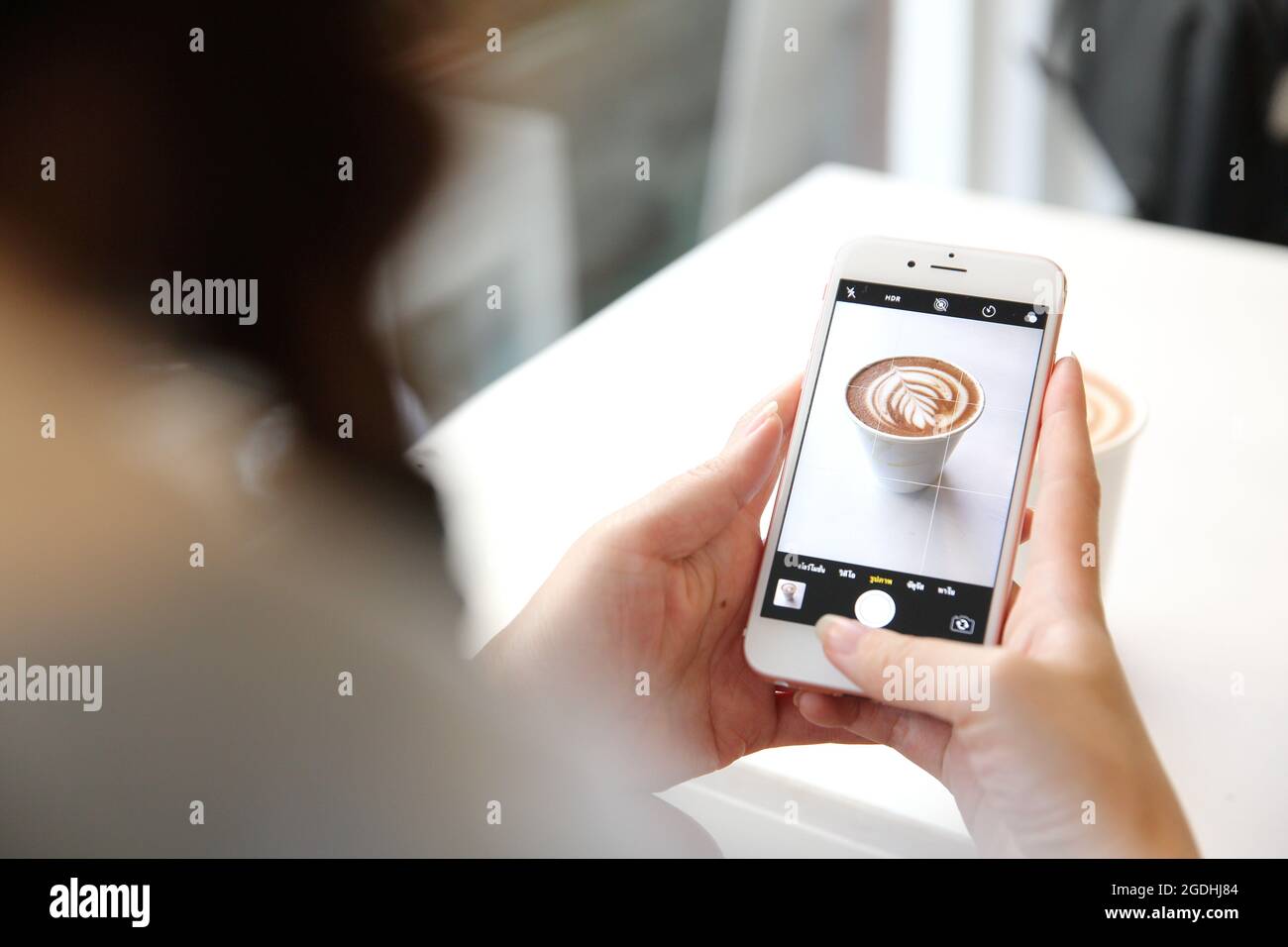 Junge Frau, die mit dem Smartphone Kaffee fotografiert Stockfoto