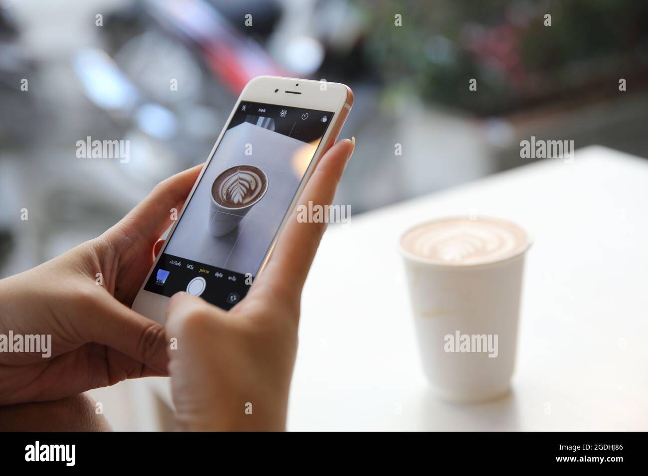 Junge Frau, die mit dem Smartphone Kaffee fotografiert Stockfoto