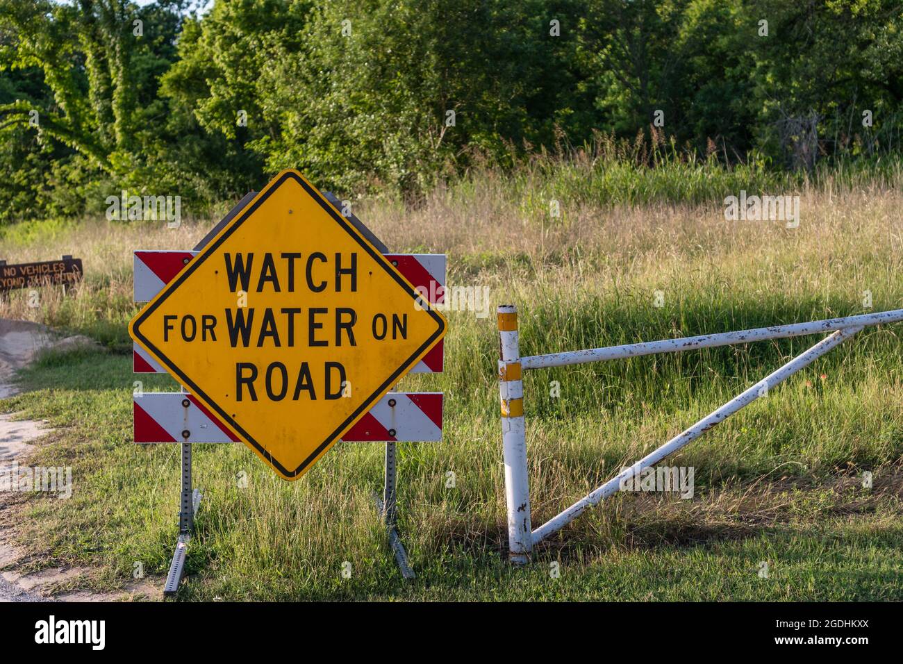 Schild mit der Aufschrift „Watch for Water on Road“ aufgrund von Überschwemmungen aufgrund des Meeresspiegelanstiegs und des Klimawandels Stockfoto