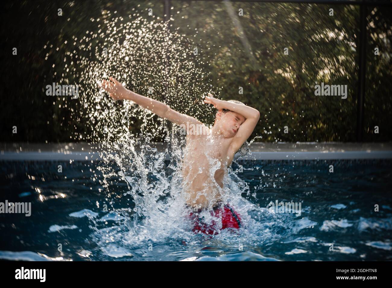 Glücklicher 8 Jahre alter Junge, der im Sommer Spaß in einem Schwimmbad hat Stockfoto