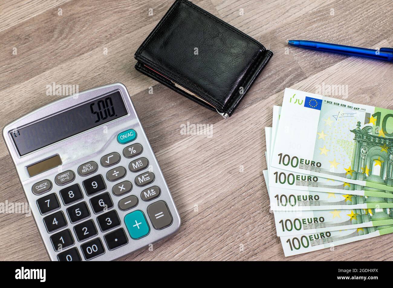 100 Euro Scheine, Taschenrechner, Potrafofli und Stift auf Holztisch Stockfoto