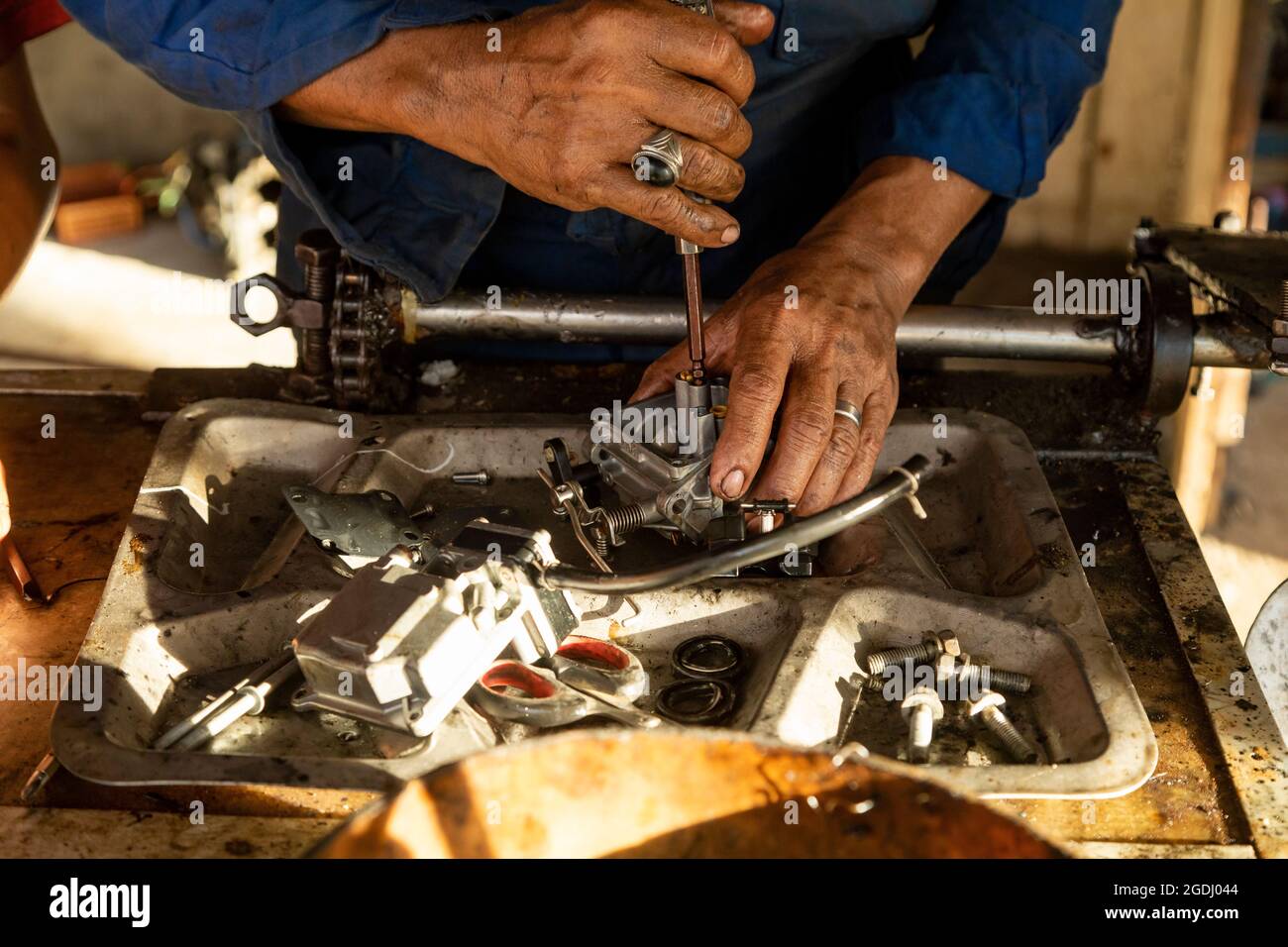Waisai, Indonesien - 16. Oktober 2019: Ein Mann, der als Mechaniker arbeitet, fixiert geschickt den Vergaser eines Bootsmotors in seiner Werkstatt Stockfoto