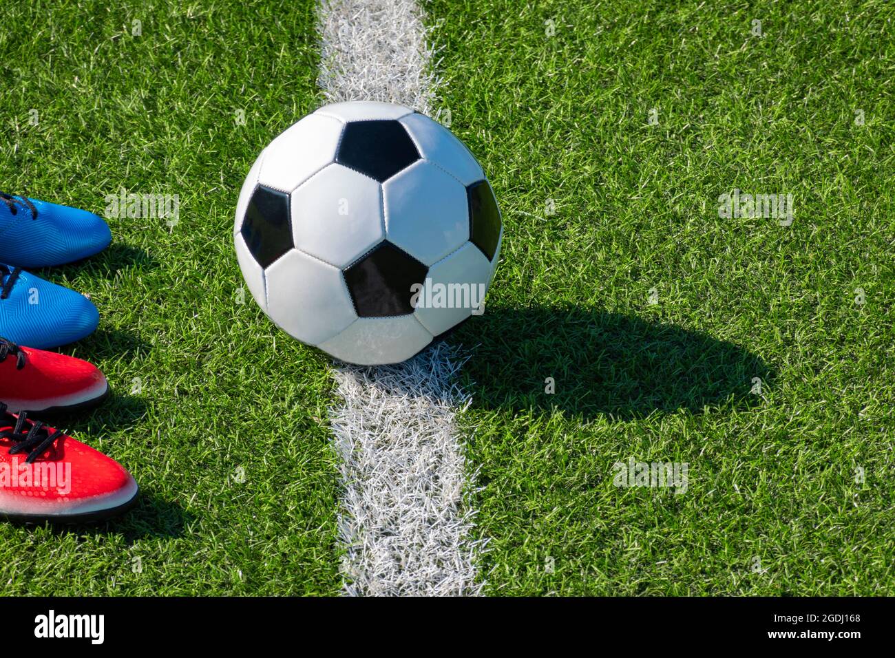 Fußballhintergrund. Fußball und zwei Fußballschuhe auf Kunstrasen-Fußballfeld Stockfoto