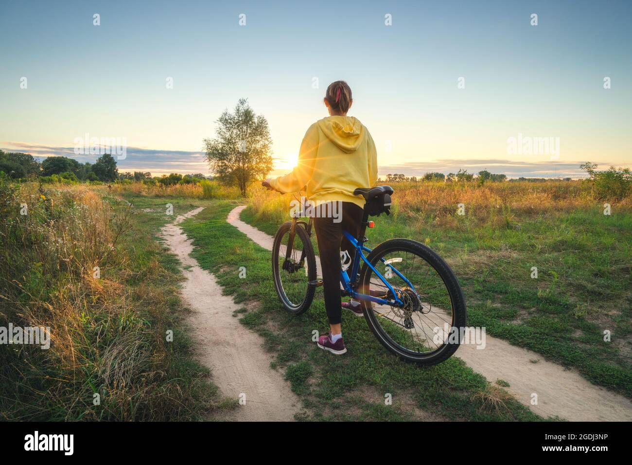 Frau, die im Sommer in der Langlaufstraße mit dem Mountainbike unterwegs ist Stockfoto