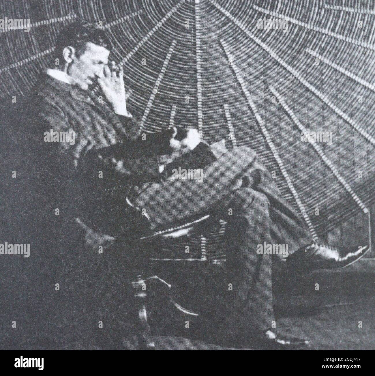 Nikola Tesla in der Nähe der Spiralspule seines Hochfrequenztransformators. Stockfoto
