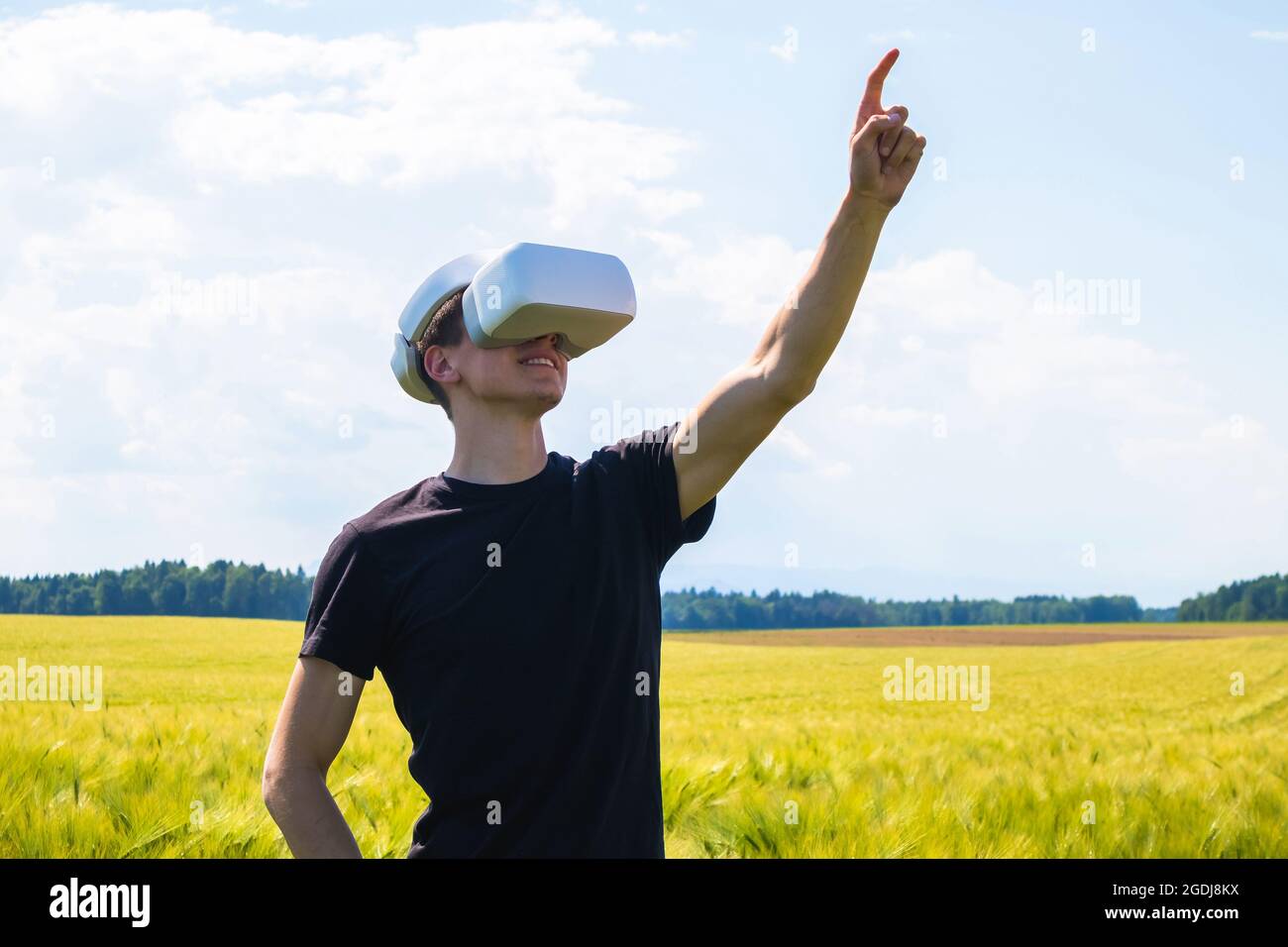 Mann mit Virtual-Reality-Brille draußen in der Natur auf einem Weizenanbaugebiet. Stockfoto