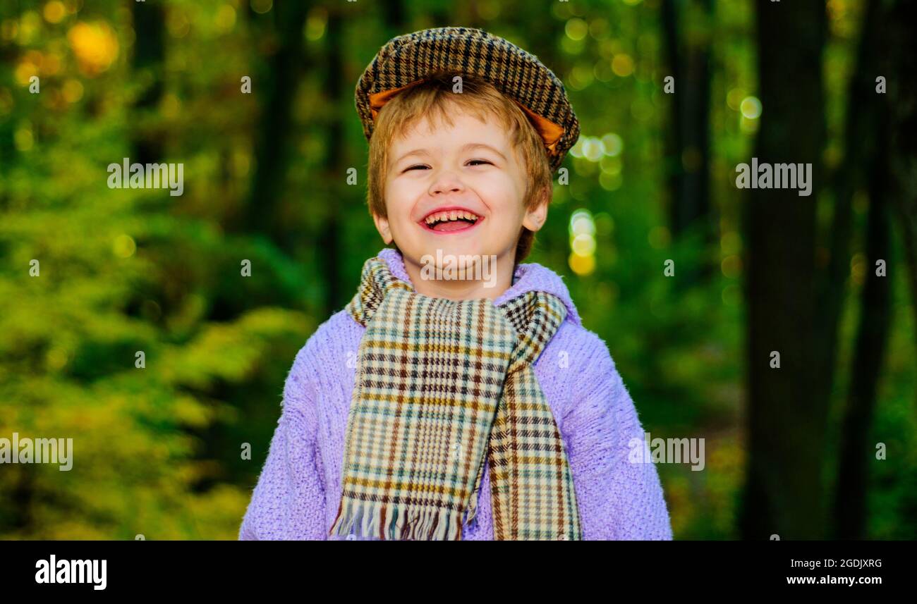 Niedliches Kind in warmer Kleidung. Kleines Kind im Herbstpark. Lächelnder Junge in Pullover, Hut und Schal. Stockfoto