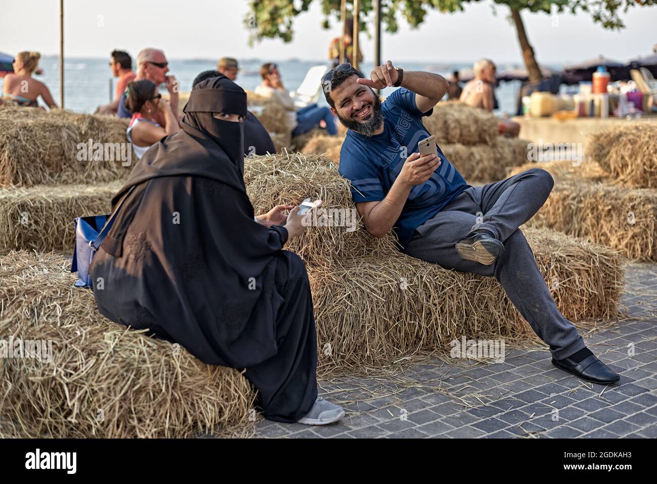 Muslim Paar mit Frau in voller Burka, mit Smartphone-Kommunikation während der Entspannung im Urlaub. Thailand S. E. Asien Stockfoto