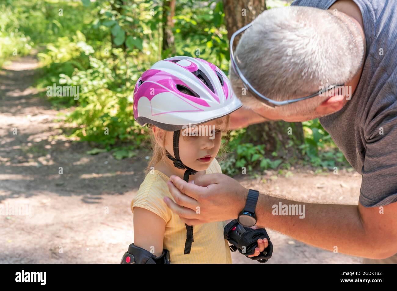 Papa zieht Tochter schützende Sportkleidung an. Stockfoto