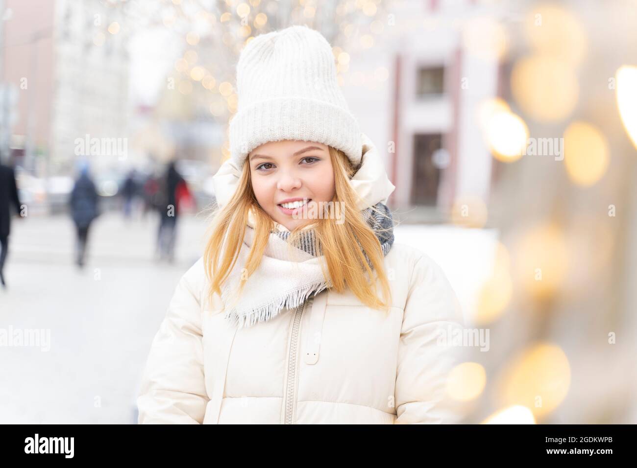 Porträt eines schönen kaukasischen blonden Mädchen 16 Jahre alt vor dem Hintergrund der Weihnachtsbeleuchtung. Lichttaste Stockfoto