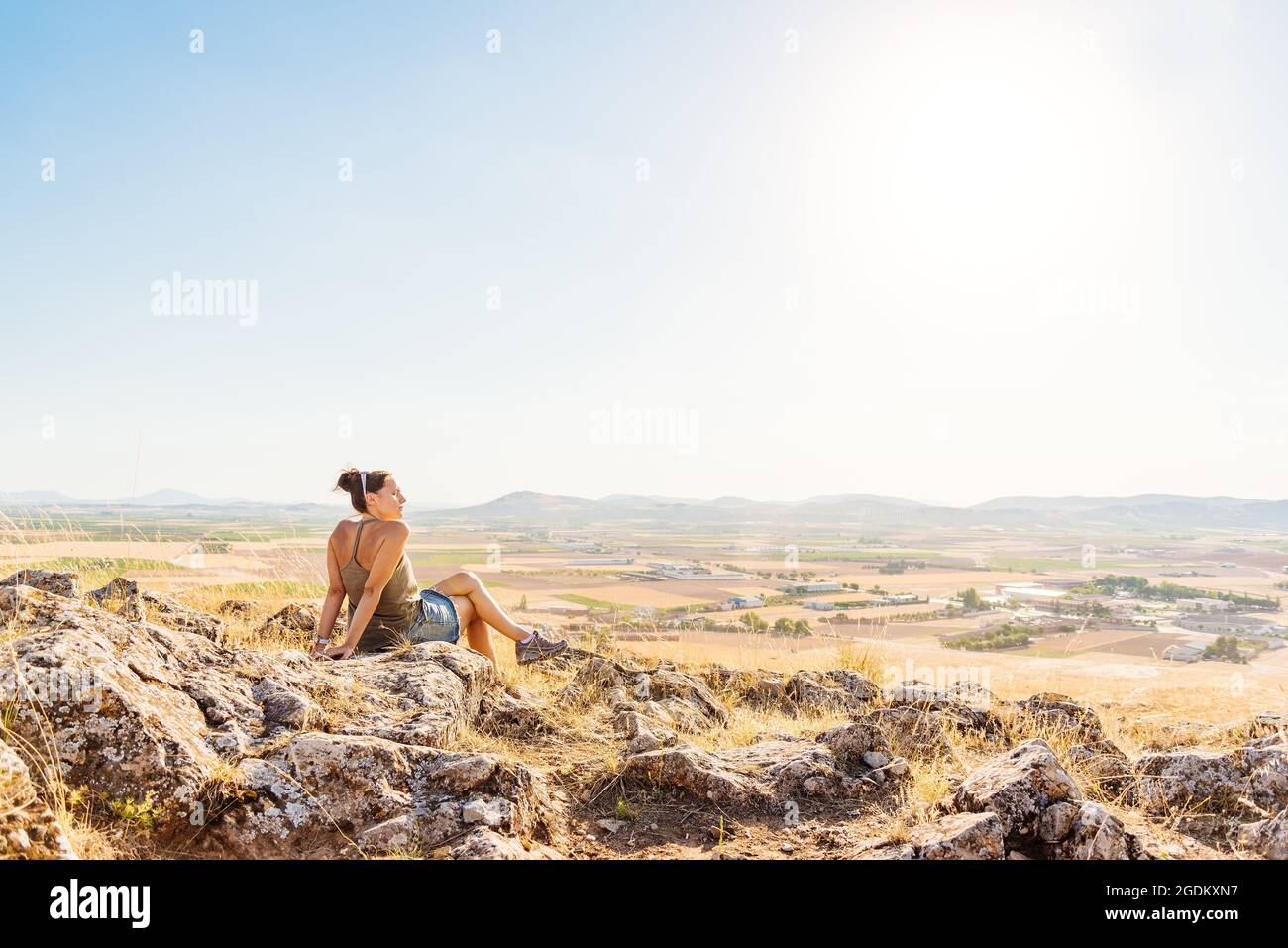 Frau, die auf einem Hügel mit Blick auf die Landschaft sitzt Stockfoto