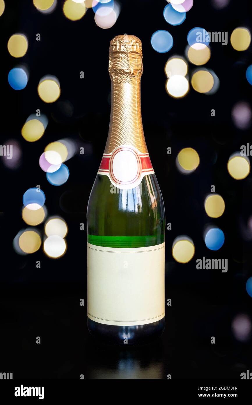 Eine Flasche korkierten Champagner mit leerem Etikett auf schwarzem Hintergrund mit hellen Lichtern. Blick mit Platz für Ihre Grüße Stockfoto