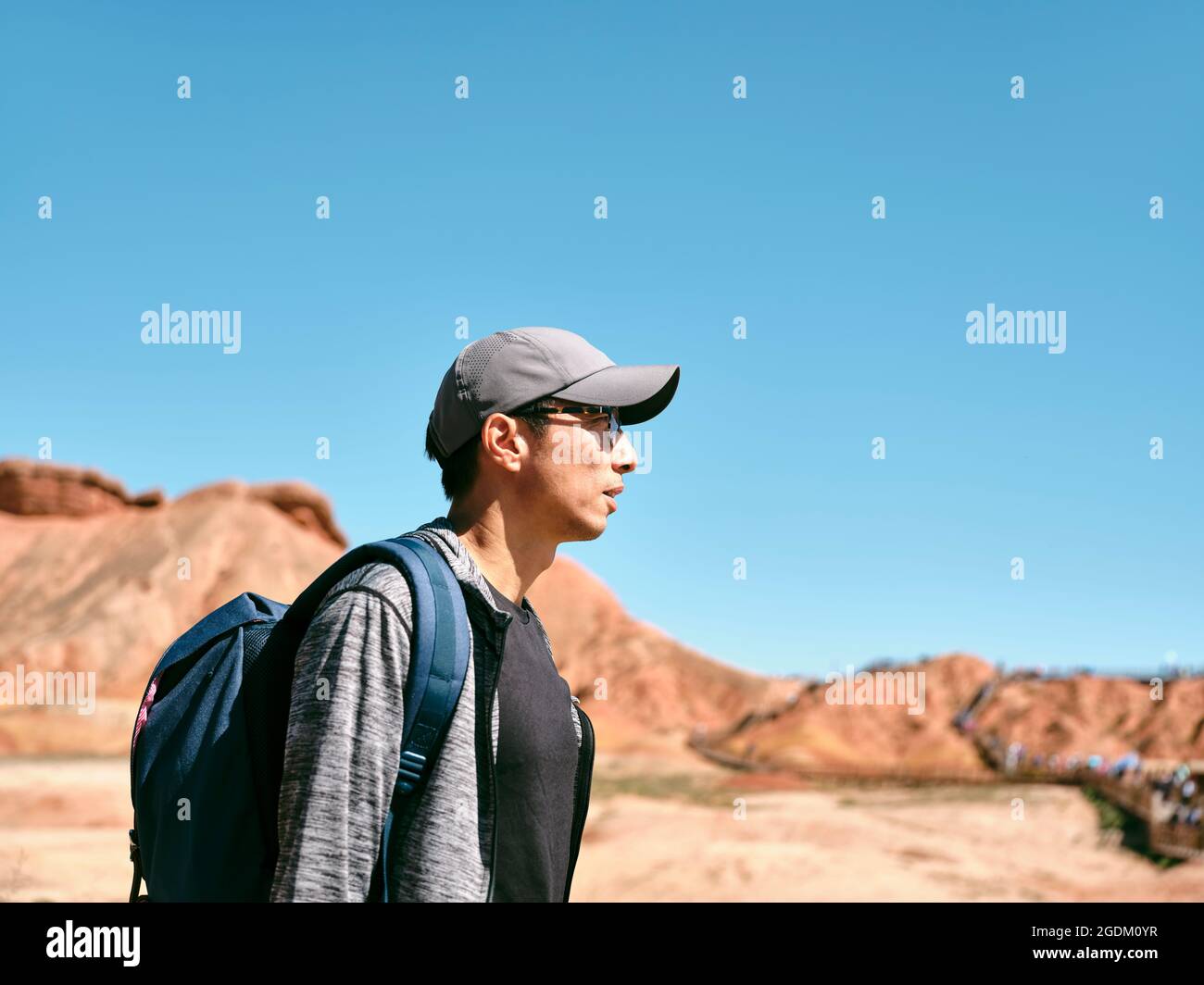 asiatischer Mann touristischer Rucksacktourist, der im nationalen geologischen Park spazierengeht, Seitenansicht Stockfoto