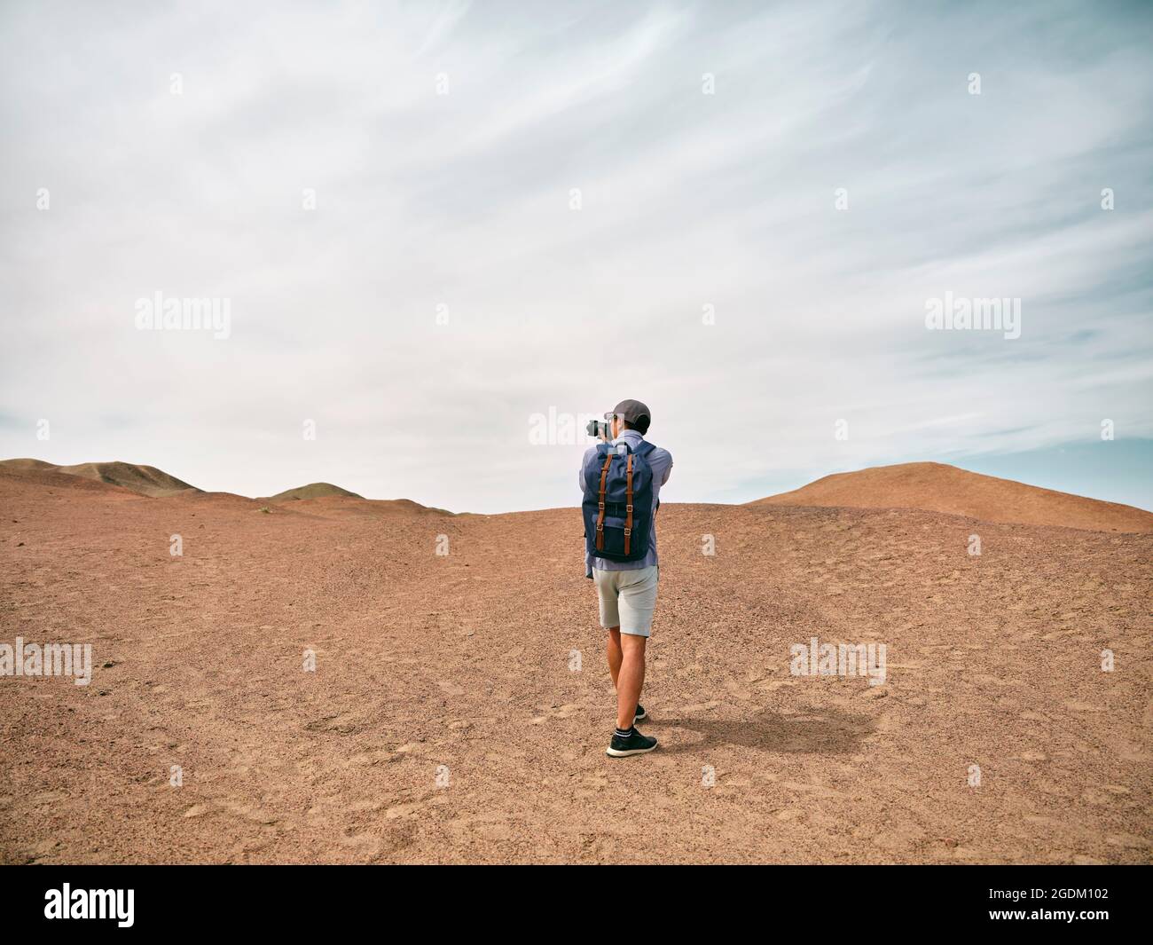 asiatischer, männlicher Backpacker-Landschaftsfotograf, der ein Foto auf einem Hügel macht, Rückansicht Stockfoto