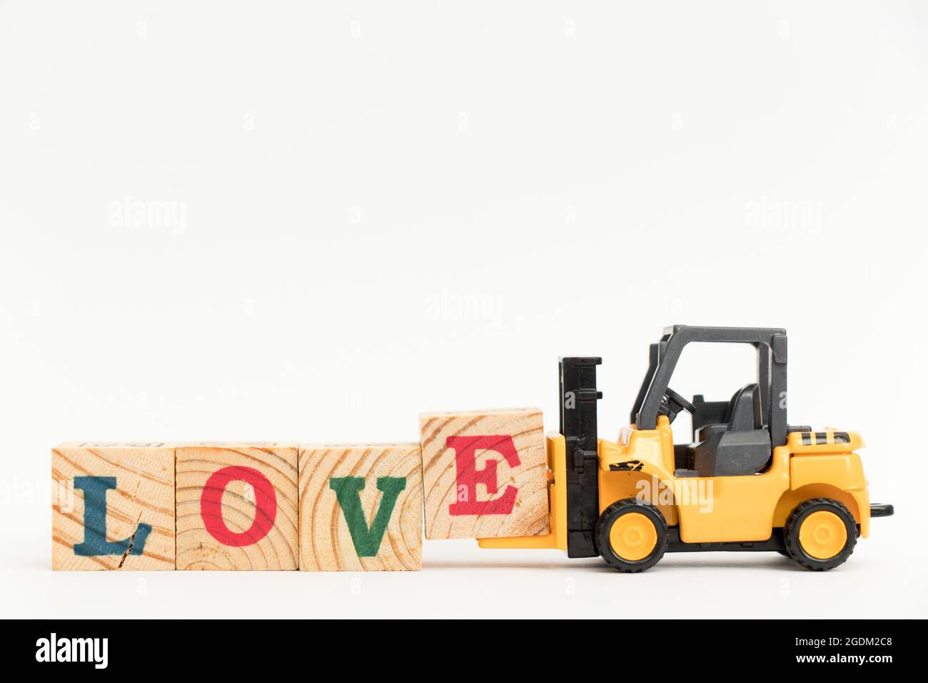Spielzeug Gabelstapler halten Holz schreiben Block E zu Wort Liebe auf weißem Hintergrund abgeschlossen Stockfoto