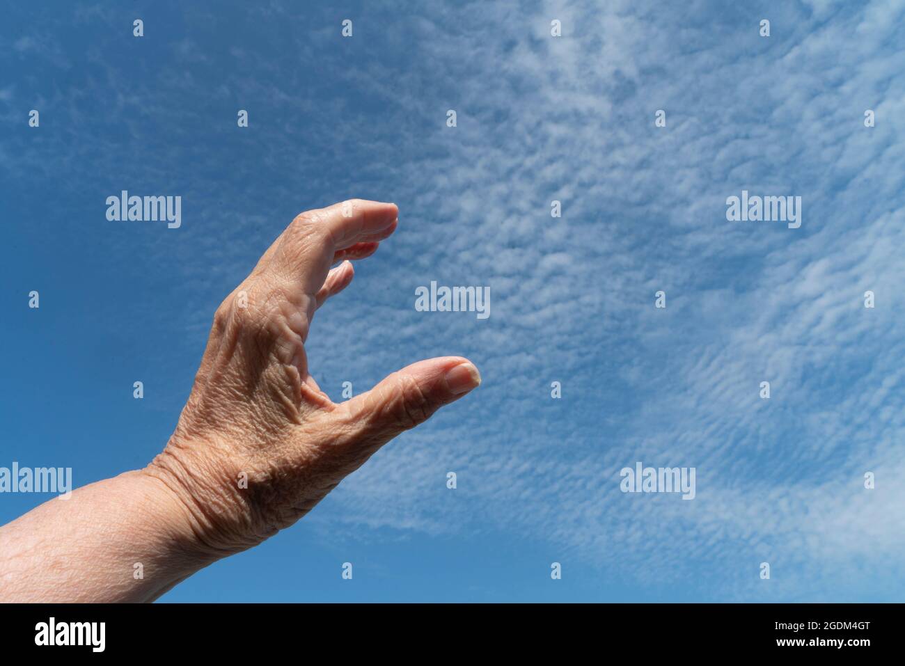 Nach dem Himmel greifen: Die Hand einer Frau, die versucht, ein Stück vom Himmel zu erfassen oder zu messen. 13. August 2021 Stockfoto