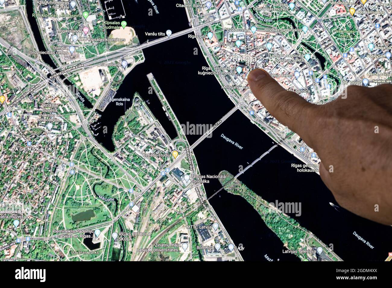 Udine, Italien. 21. August 2021. Die Google Maps-Satellitenansicht von Riga, der Hauptstadt Lettlands, wird mit einem Finger angezeigt Stockfoto