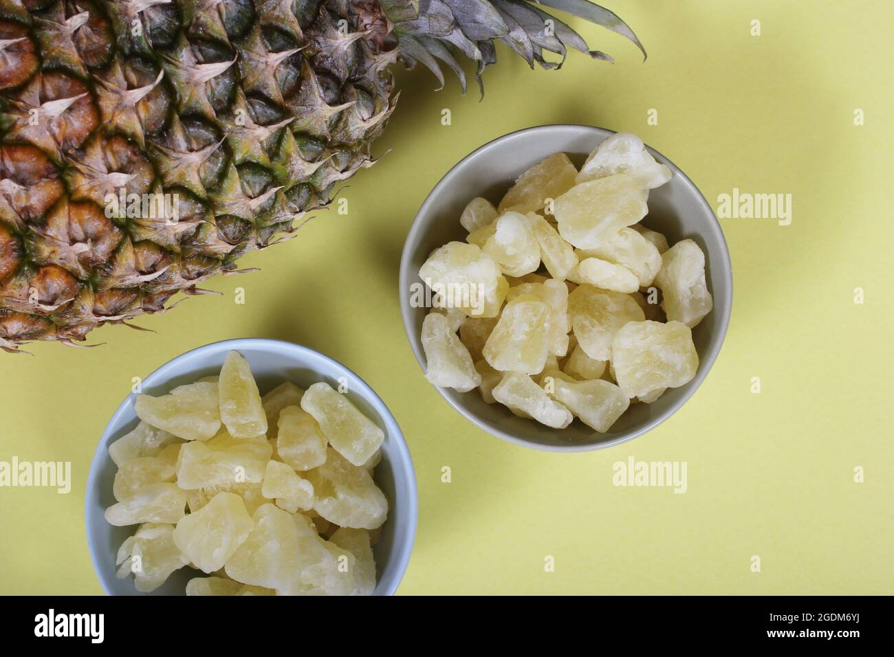 Frische und getrocknete Bio-Ananas auf gelbem Hintergrund Closeup Stockfoto