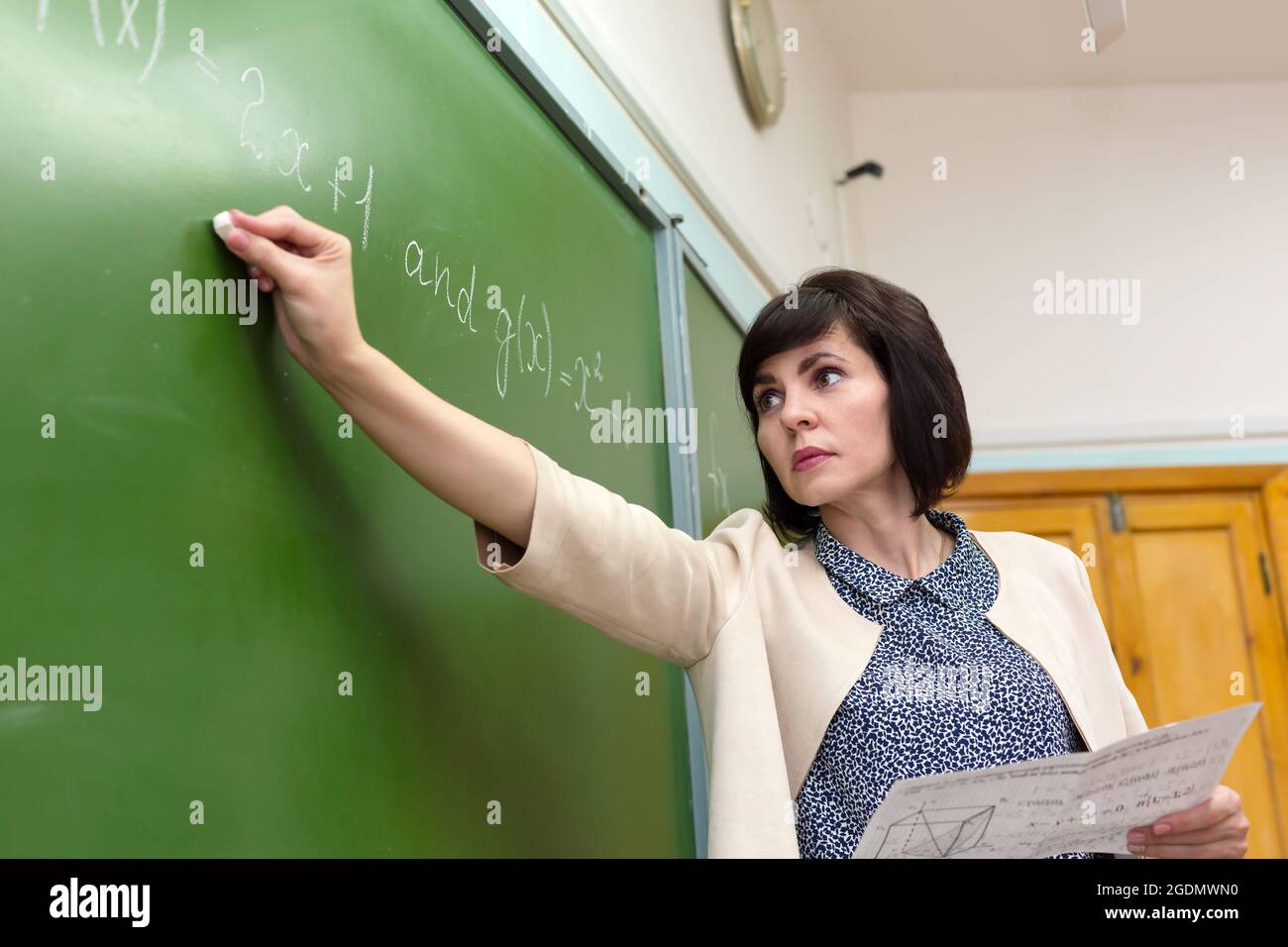 Eine Lehrerin schreibt eine mathematische Formel auf eine Tafel. Stockfoto