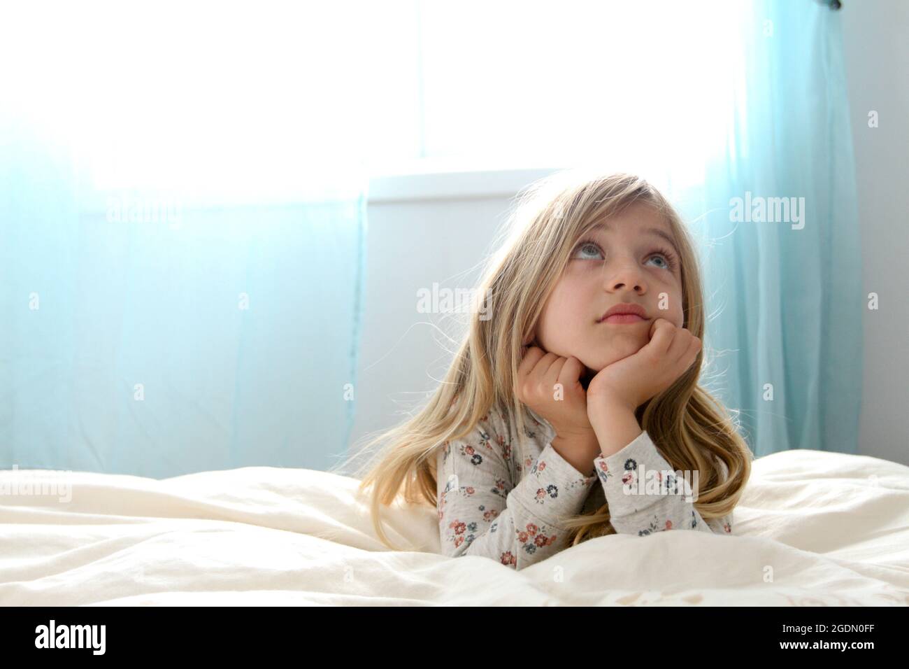 Junges Mädchen von sieben Tagträumen in ihrem Schlafzimmer Stockfoto