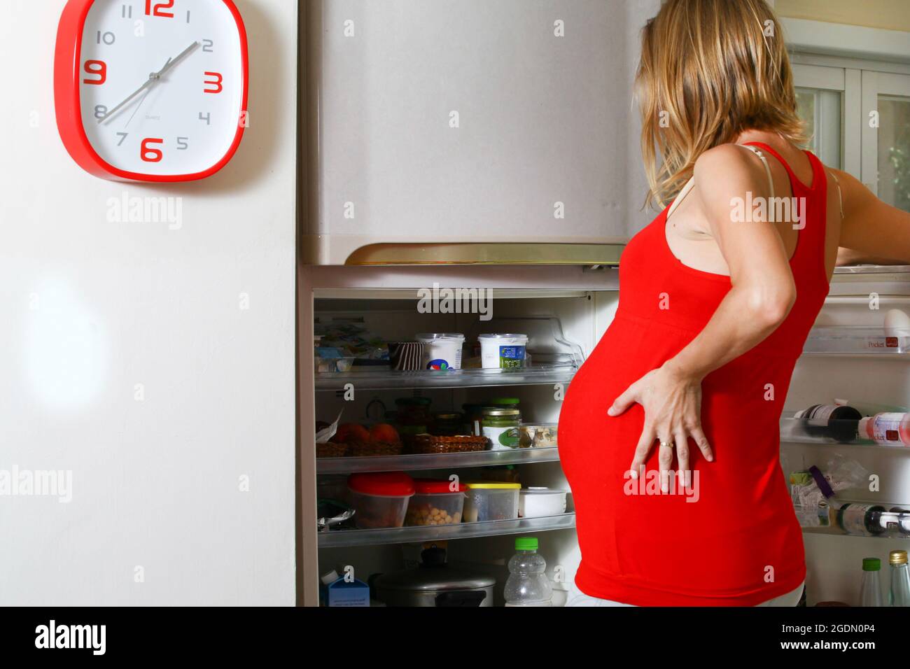 Die sehnende Schwangerin sucht im Kühlschrank nach Nahrung Stockfoto