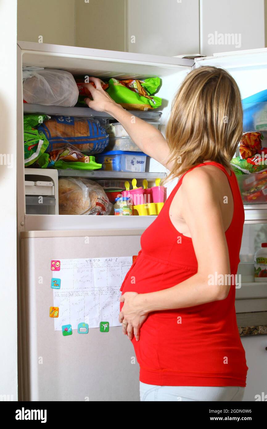 Die sehnende Schwangerin sucht im Kühlschrank nach Nahrung Stockfoto