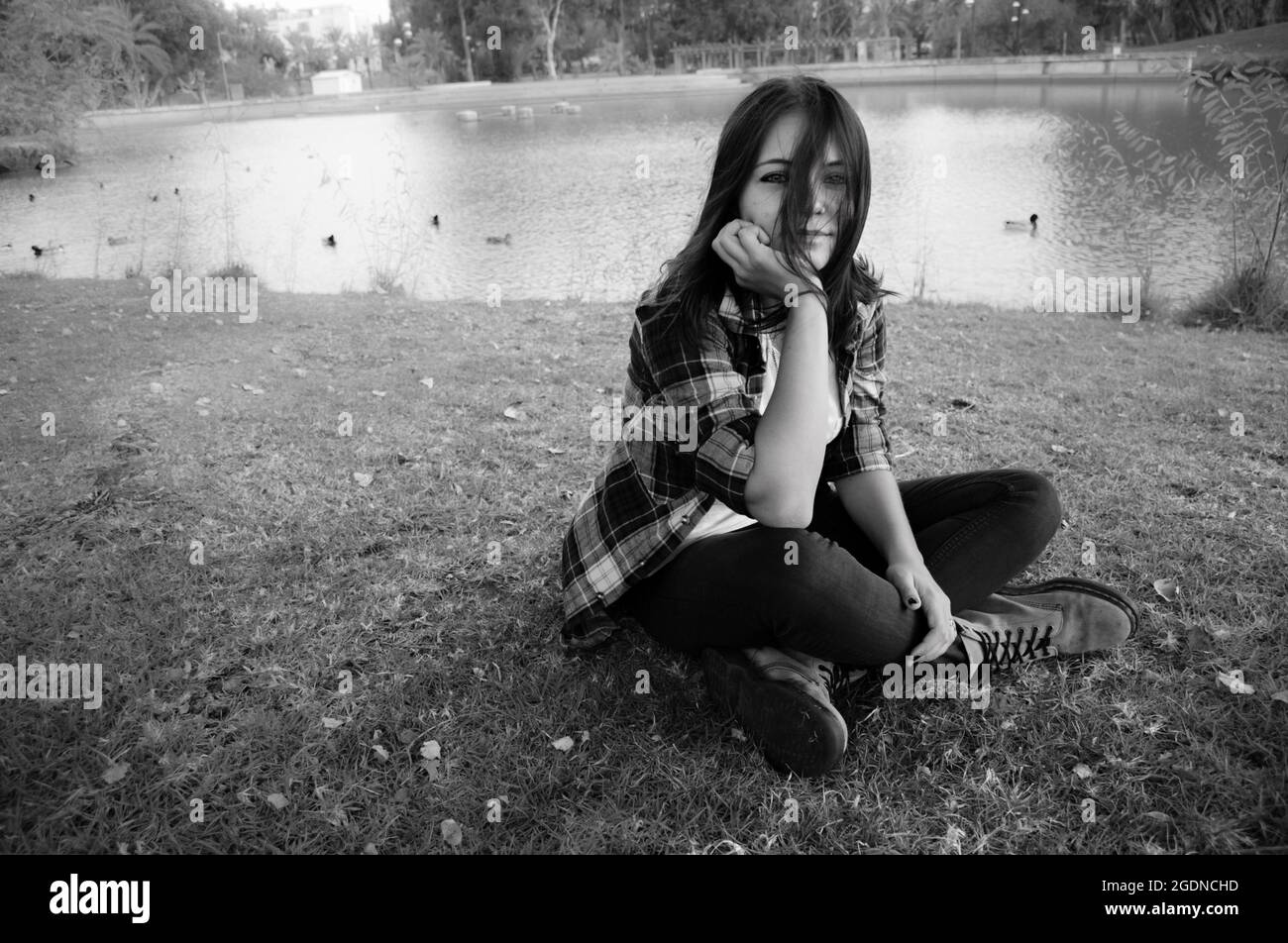 moody Bild einer jungen 25-jährigen Frau allein in einem Park Stockfoto