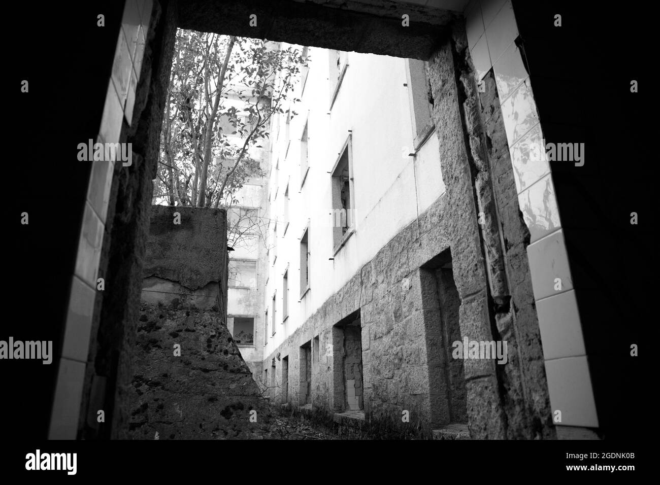 Innen- und Außenansicht eines alten Tuberkulosekrankenhauses an einem Berghang, aus Granitstein, verlassen, geplündert, verbrannt und sehr abgeschreckt Stockfoto