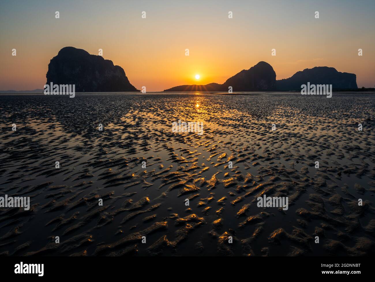 Sandwellen-Textur mit Spiegelung des Sonnenuntergangs am Strand von Pak Meng, Trang, Thailand Stockfoto