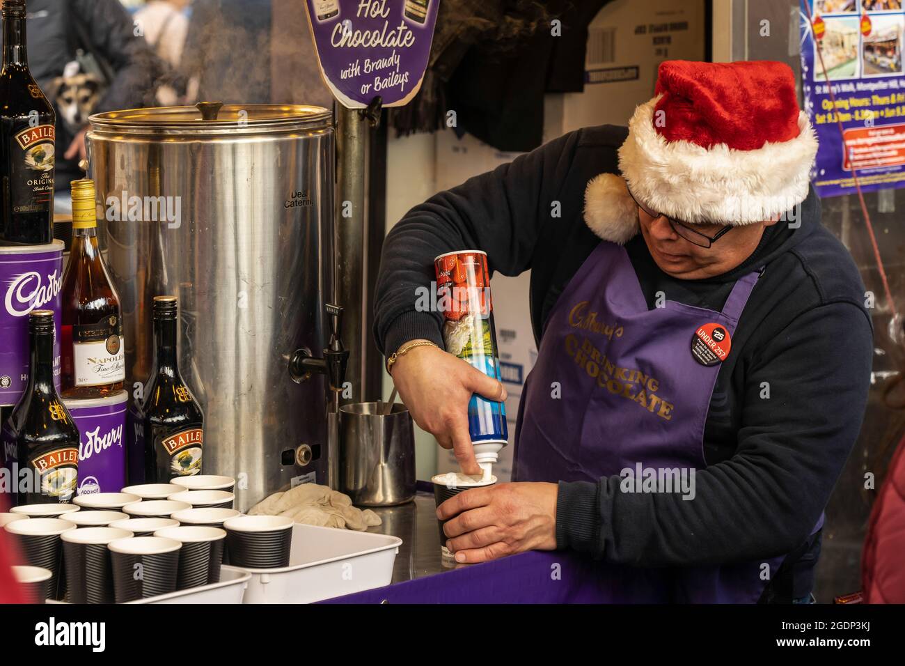 Der Weihnachtsmarkt-Ladenbesitzer trägt einen Hut von der Santa Claus-Creme auf einer kleinen Tasse heißer Schokolade, Harrogate North Yorkshire, England, Großbritannien. Stockfoto
