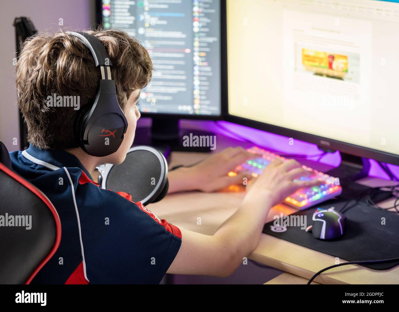 Junge, der am PC sitzt und Kopfhörer trägt und während der covid-19-Sperre am Online-Lernen teilnimmt, 2021. Stockfoto