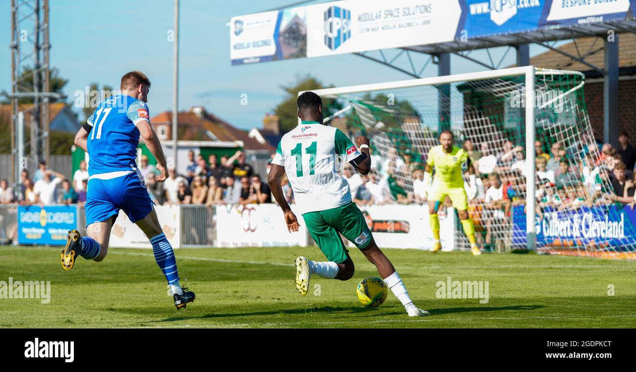 Fußball-Action vom Bognor Regis Town Football Club (Rocks) gegen Bishops Stortford. Zwei Spieler im grünen und blauen Streifen laufen auf das Tor zu. Stockfoto