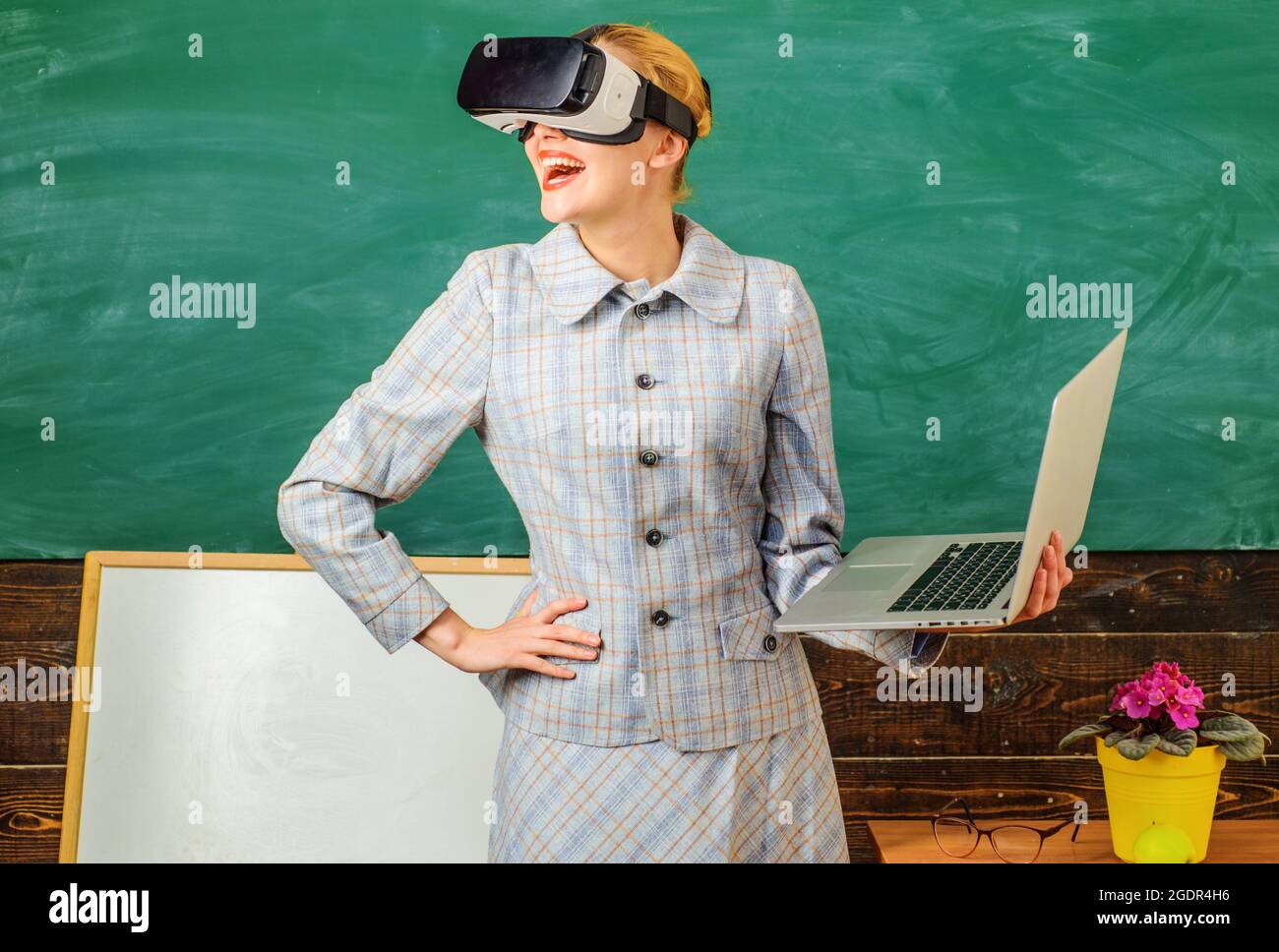 Lächelnder Lehrer mit Laptop in vr-Headset. Digitale Bildung. Moderne Technologien in der intelligenten Schule. Glücklicher Lehrer im Klassenzimmer. Stockfoto