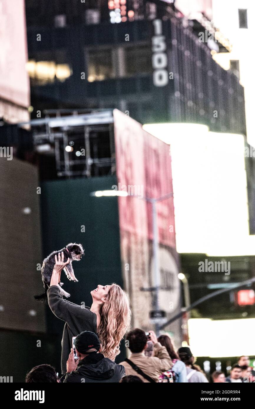 Eine Frau und ihr Hund feiern einen Abend am Times Square, New York City, USA. Stockfoto