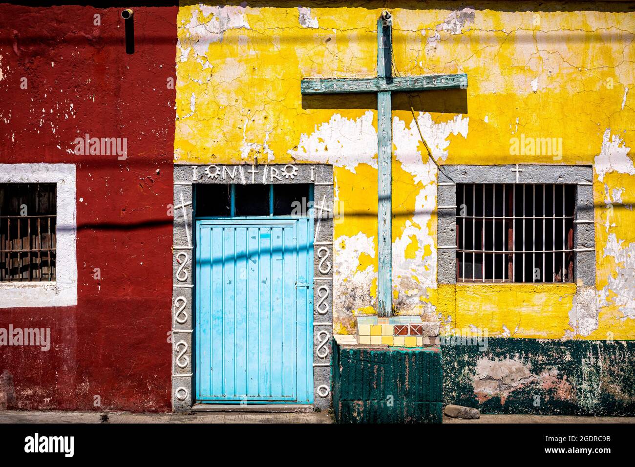 Buntes Haus mit Kreuzung entlang der Straße nach Guadalupe Victoria in Puebla, Mexiko. Stockfoto