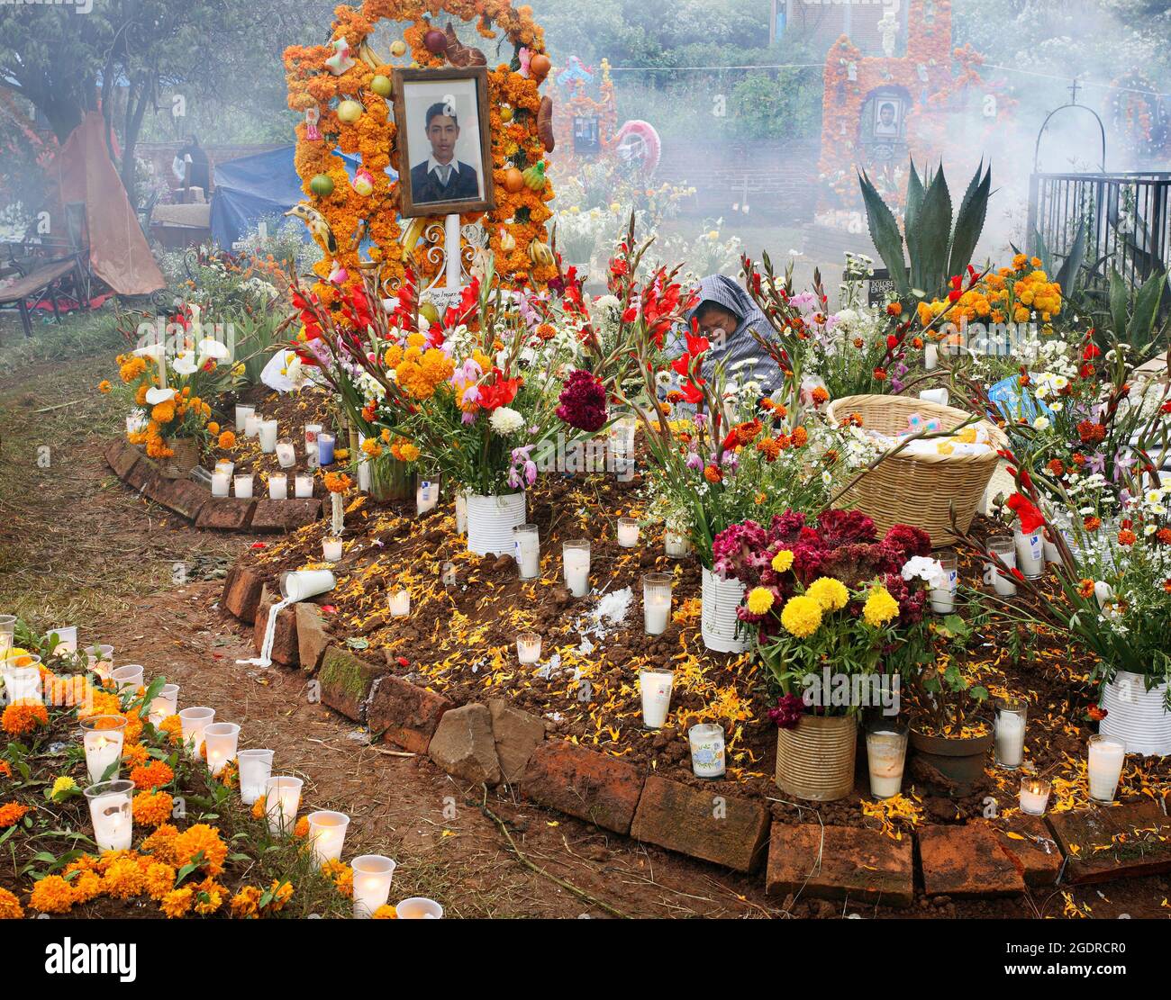 Eine Purepecha-Mutter sitzt am Altar ihres Sohnes während des Tages der Toten in Tzintzuntzan, Michoacan, Mexiko. Stockfoto