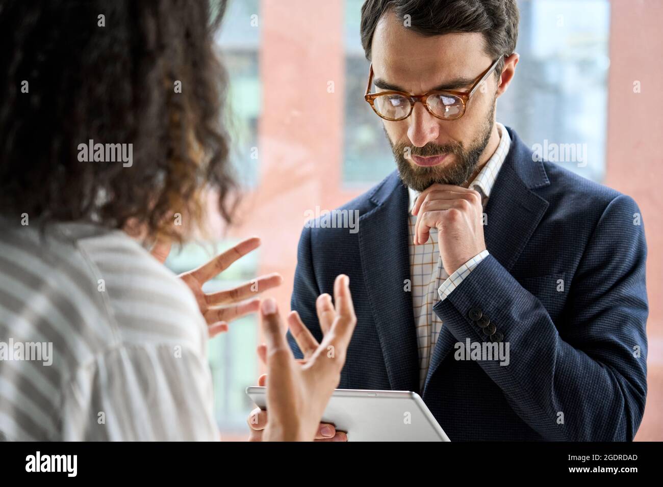 CEO hält Tablet-Gerät und hört der weiblichen Führungskraft zu, wie sie das Projekt diskutiert. Stockfoto