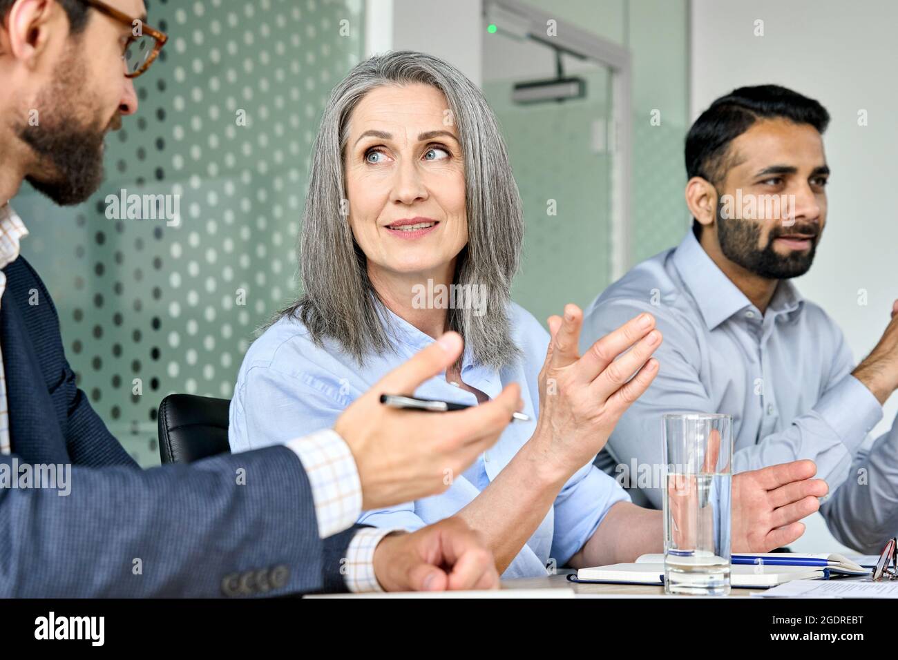 Lächelnde weibliche geschäftsführerin, die beim Tischgespräch mit der Kollegin des Managers über das Projekt spricht. Stockfoto