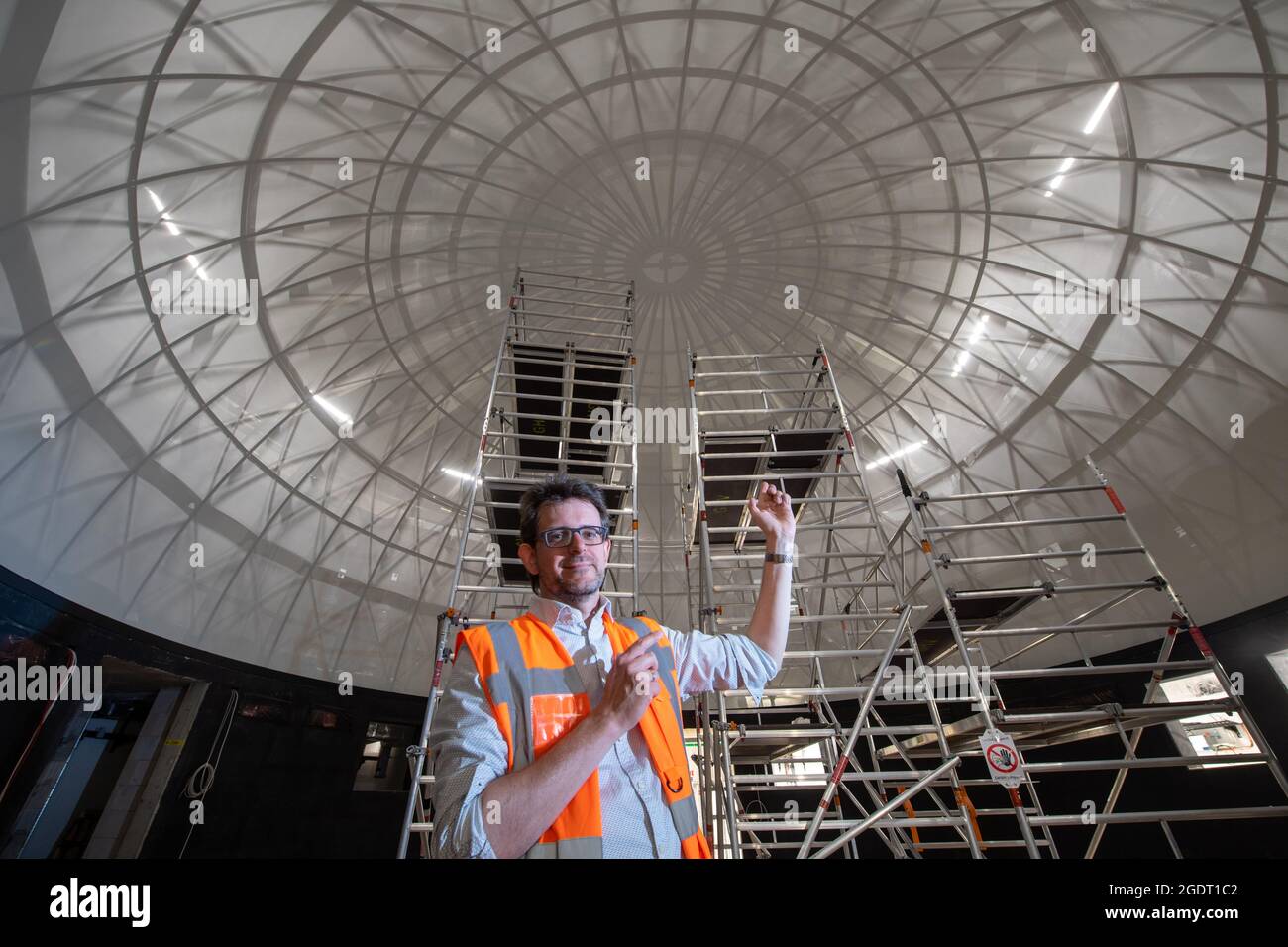 11. August 2021, Sachsen-Anhalt, Halle (Saale): Dirk Schlesier, Direktor des Planetariums, steht unter der Sternkuppel im zukünftigen Planetarium in Halle/Saale. Die Konstruktion wird eines der modernsten Planetarien in Deutschland schaffen. Die Kuppel wurde zuletzt installiert. Er besteht aus 144 Aluminiumsegmenten und misst an seiner Basis zwölf Meter im Durchmesser. Die sechs Tonnen schwere Kuppel wurde in Ohio, USA, hergestellt und befindet sich im Herzen des Planetariums. Rund 100 Zuschauer sollen ab Frühjahr 2022 unter dem Firmament sitzen und den Nachthimmel betrachten können. In der Zwischenzeit kostet der Bau h Stockfoto
