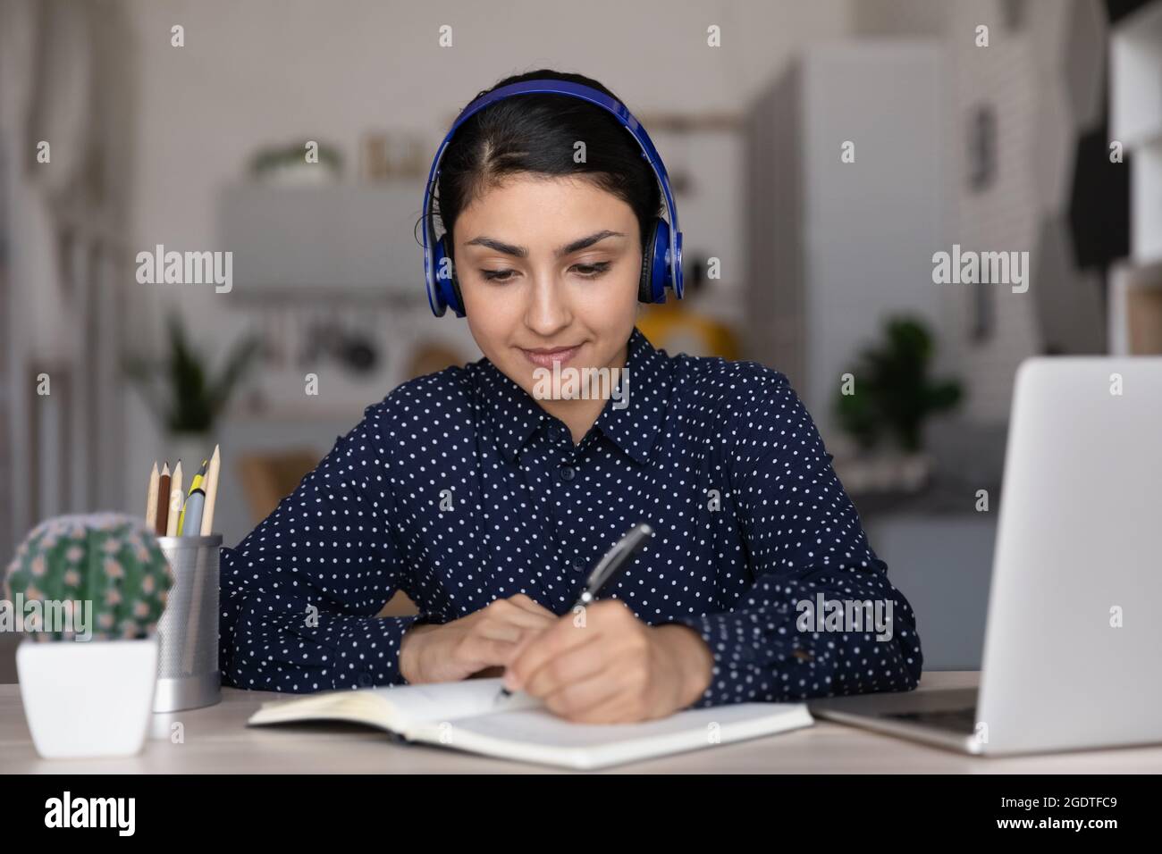 Intelligente indische Frau in Ohrhörern arbeiten online am Computer Stockfoto