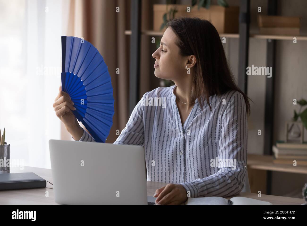 Unwell Frau arbeiten an Computer-Welle mit Handventilator Stockfoto