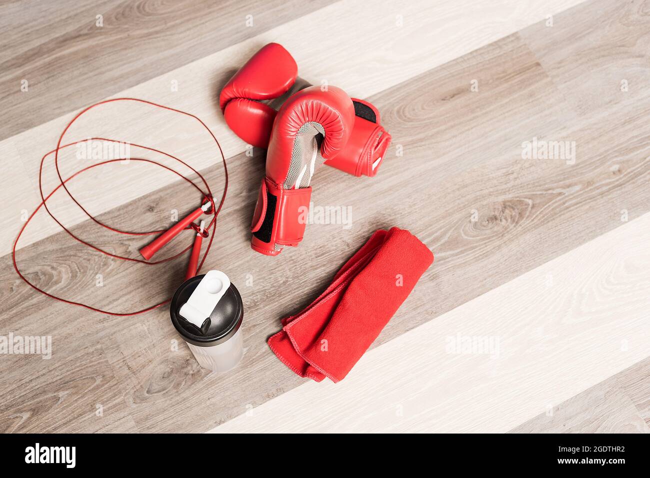 Draufsicht auf Boxhandschuhe, Seil, Flasche und ein rotes Handtuch auf einem Holzhintergrund Stockfoto