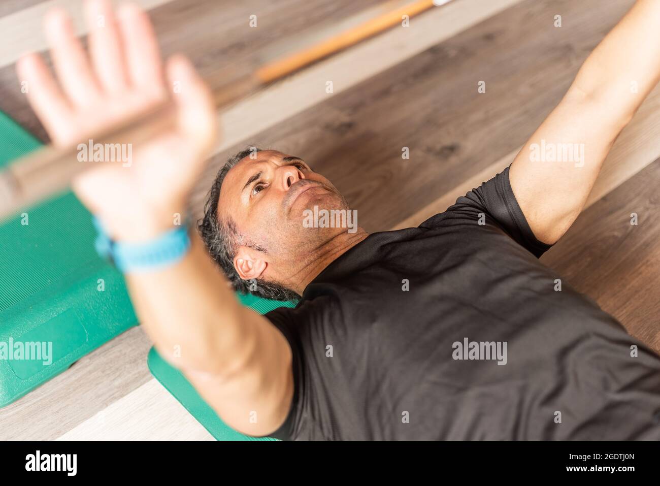 Beschnittene Vorderansicht eines erwachsenen Mannes, der auf der Bank auf der Stufe im Fitnessstudio sitzt Stockfoto