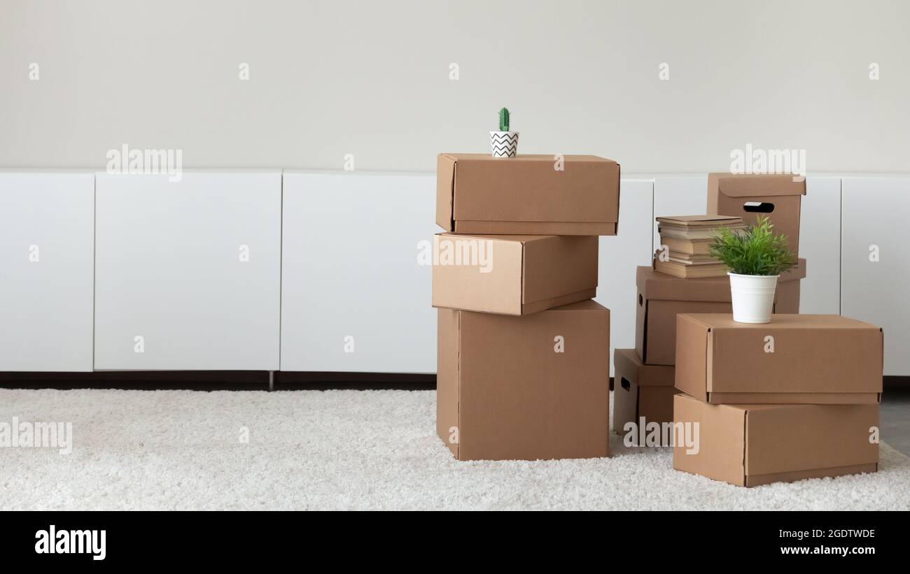 Haufen von Kisten mit Habseligkeiten im leeren Wohnzimmer gestapelt Stockfoto