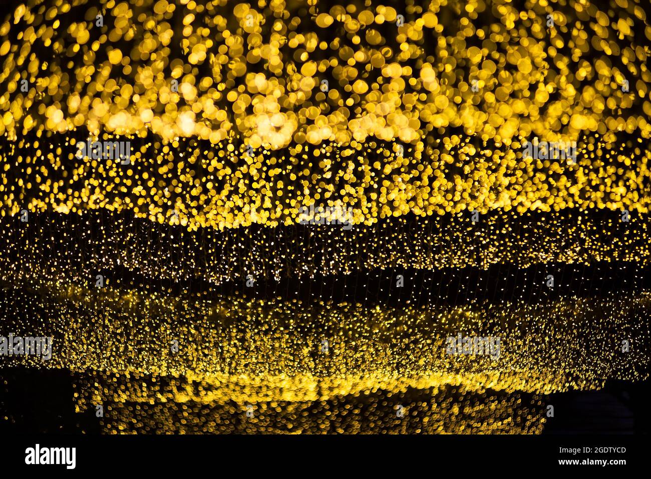 Viele Bokeh aus Glühbirnenröhre auf einer Straße in der Nacht, die wie Luxus goldener Stern Licht in dunklem Hintergrund aussehen Stockfoto