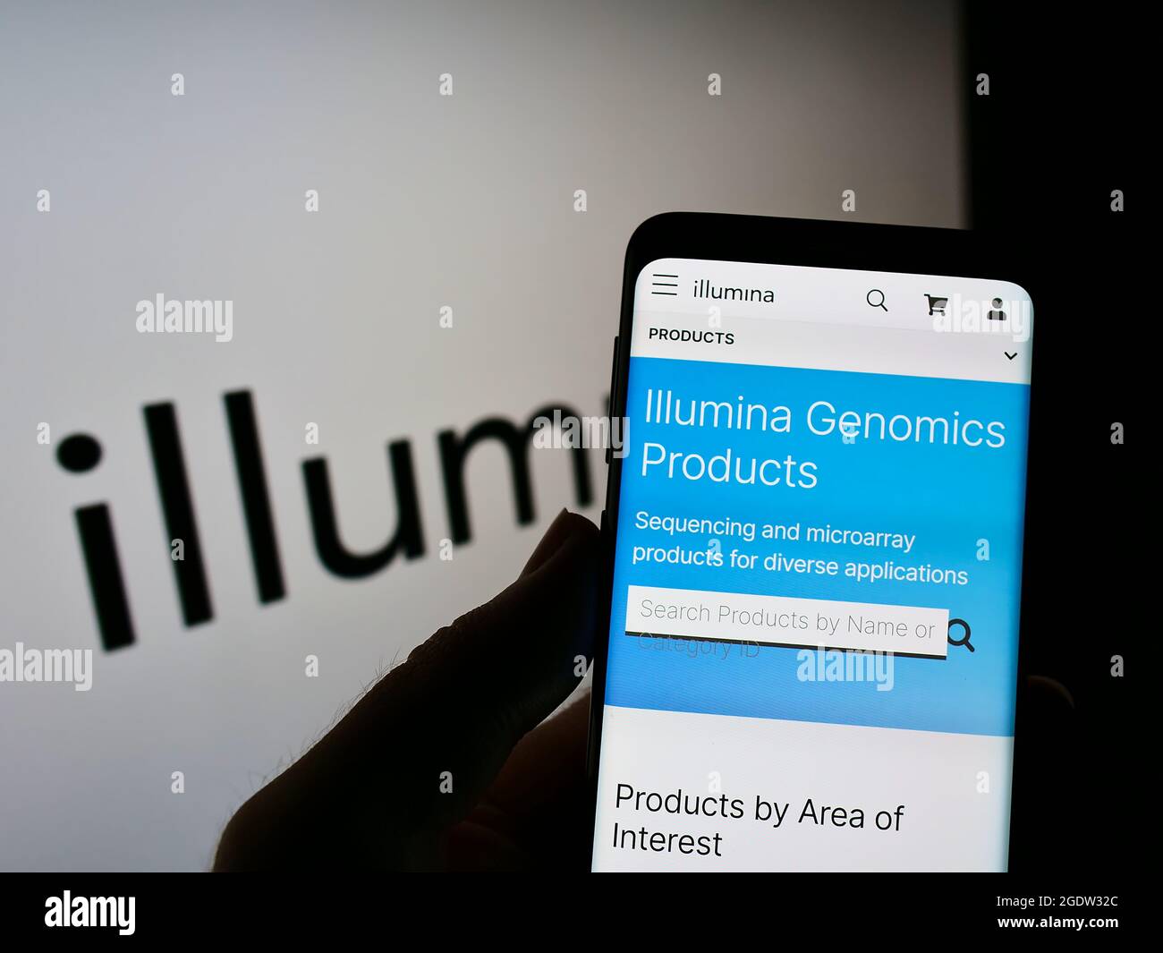 Person, die Mobiltelefon mit der Webseite des amerikanischen Genetikunternehmens Illumina Inc. Auf dem Bildschirm vor dem Logo hält. Konzentrieren Sie sich auf die Mitte des Telefondisplays. Stockfoto
